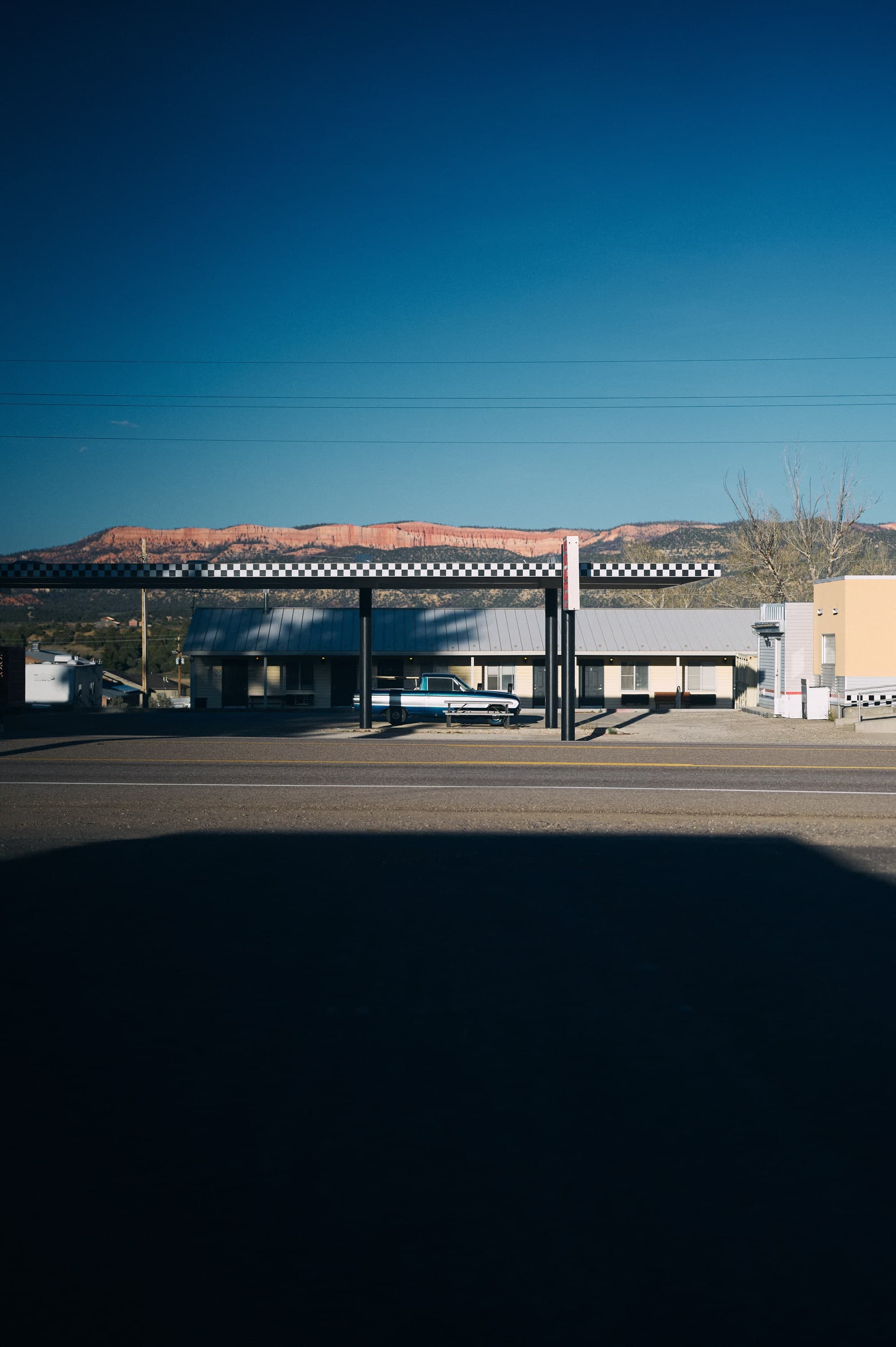 Tankstelle mit Schachbrettdach vor roten Felsen unter tiefblauem Himmel