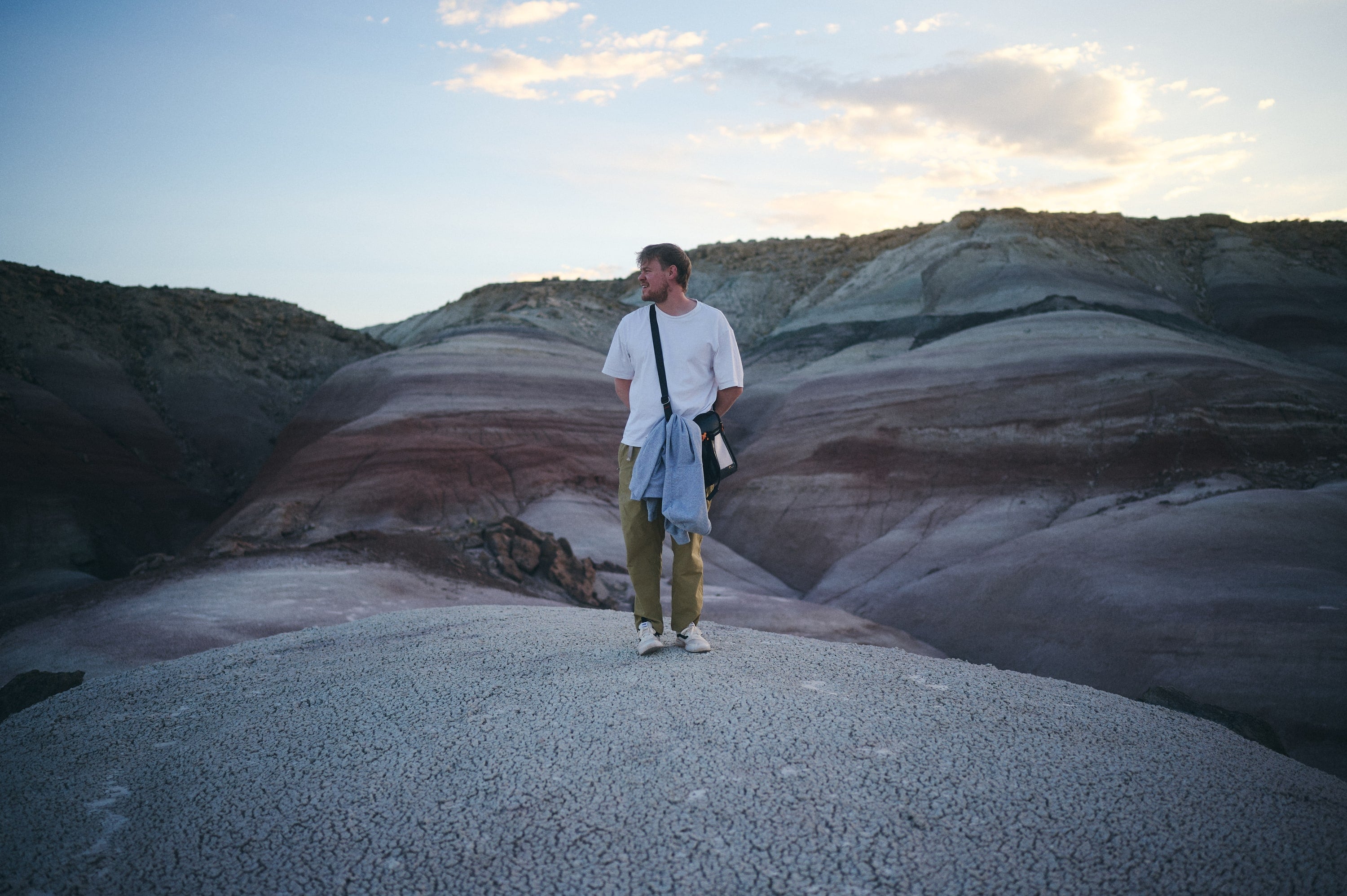 Jörn Schüler auf einer Hügelkuppe in einer gestreiften Badlands-Landschaft in Utah, im Abendlicht